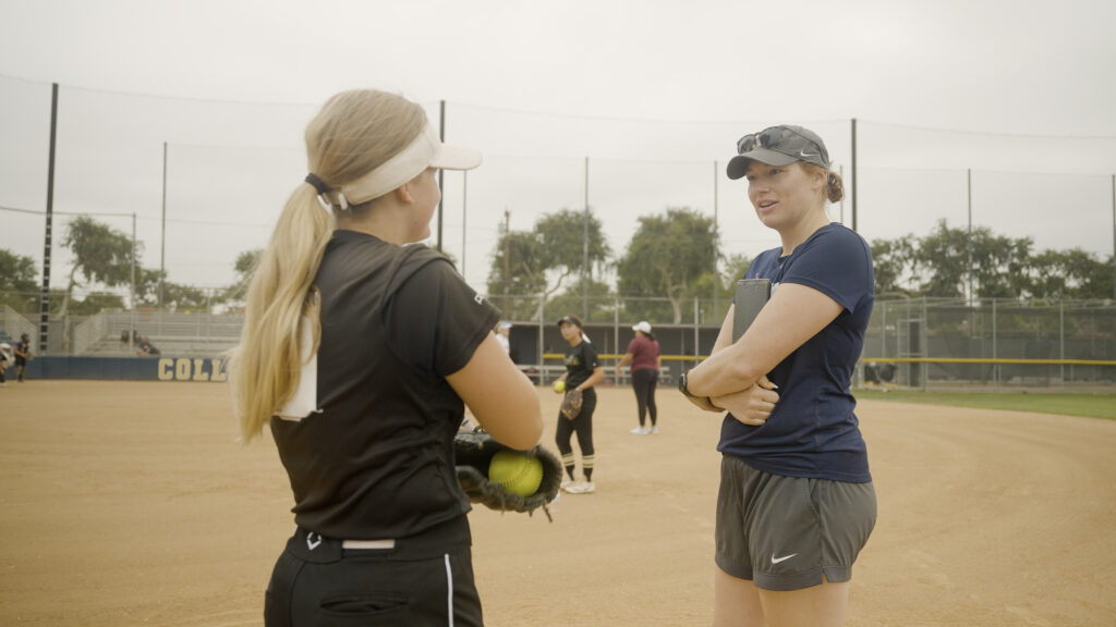 College softball coach has a recruiting conversation with athlete at camp