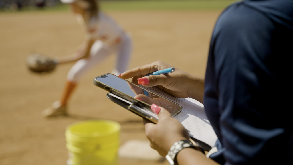College softball coach evaluating recruits at a camp.